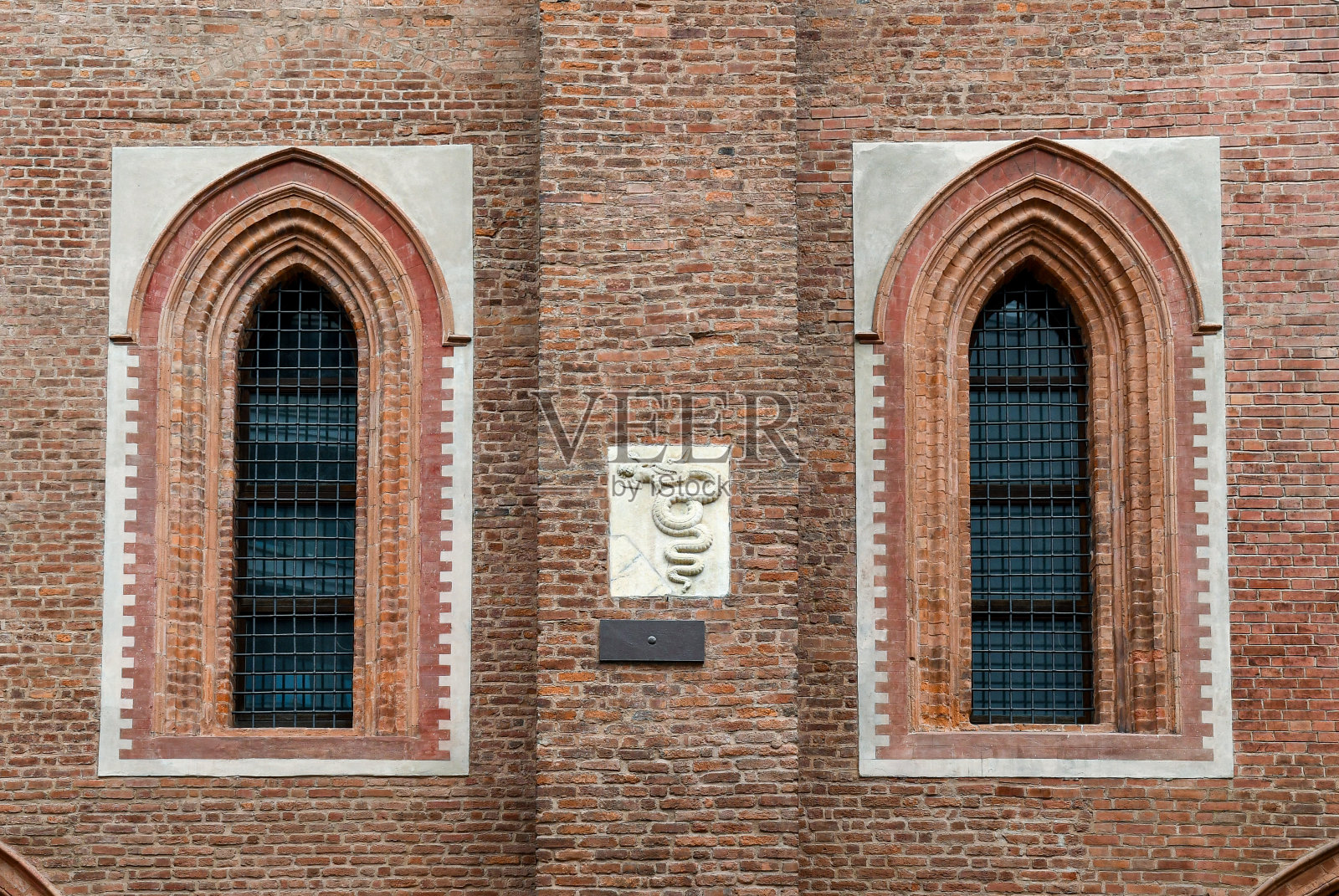 Biscione(“大草蛇”),象征着纹章和城市象征,位于意大利伦巴第米兰圣玛利亚因科罗纳塔教堂正面的一对尖顶拱形窗户之间照片摄影图片