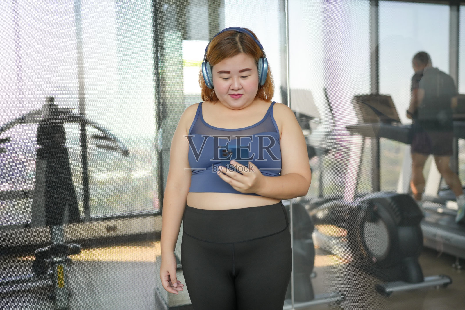 在健身房锻炼后，聪明的女性phoneÂ。肥胖的亚洲女性正在观看在线锻炼训练课。照片摄影图片