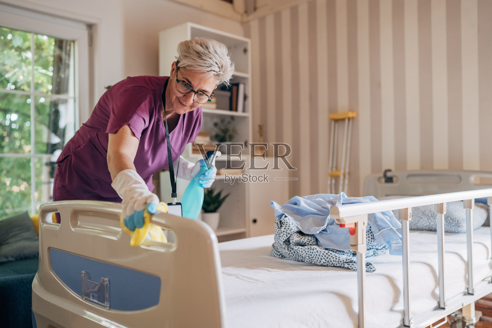 穿紫色制服的护士在给病人的病床消毒照片摄影图片