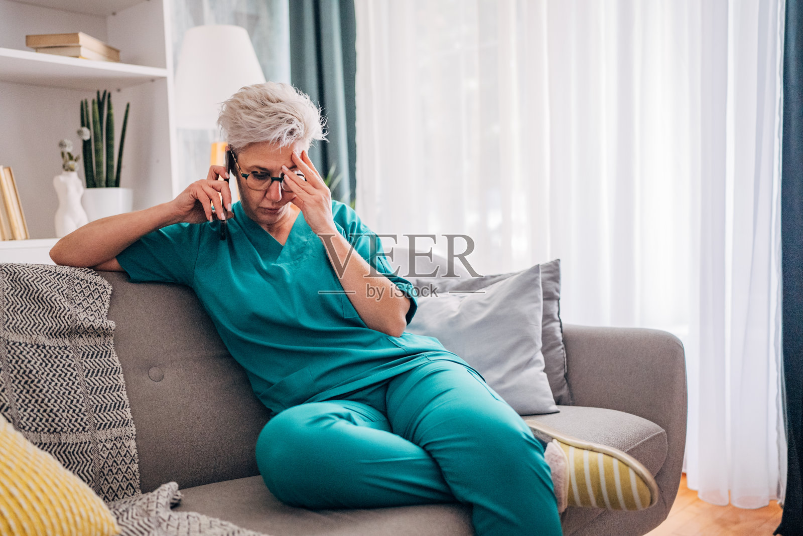 穿着绿色粗麻布的个人在沙发上打电话聊天照片摄影图片