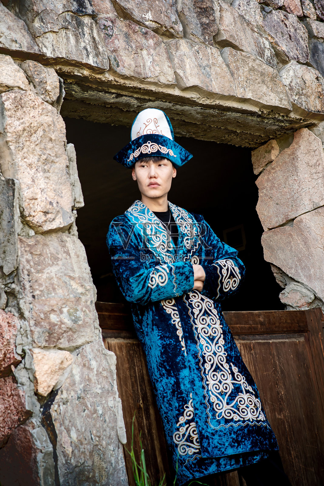 身穿民族服装、手拿长袍的哈萨克男子照片摄影图片