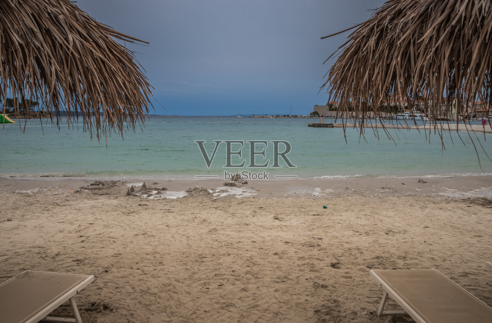 宁静的海滩与草伞和躺椅，理想的放松和娱乐照片摄影图片