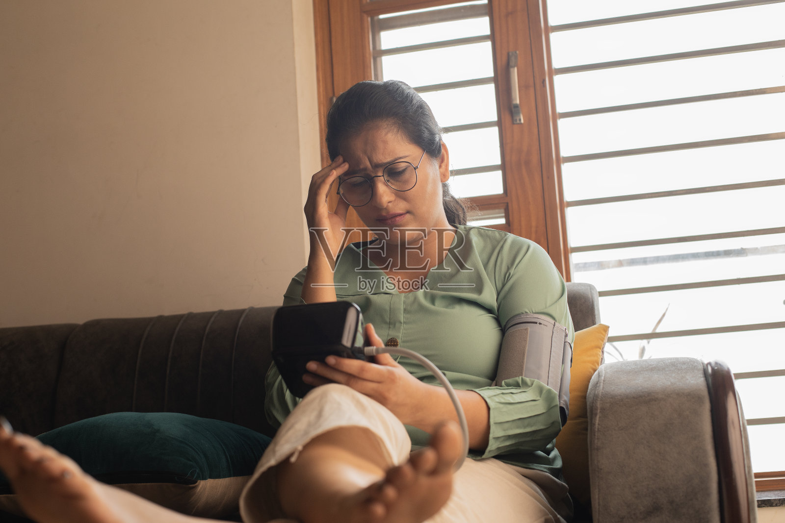 心烦意乱的女人在家里用血压计测量血压照片摄影图片