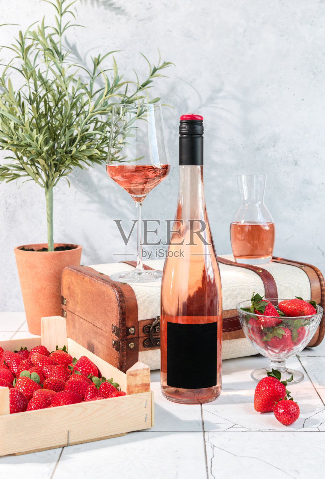 玫瑰酒瓶与葡萄酒杯和草莓在明亮的乡村厨房品酒照片摄影图片