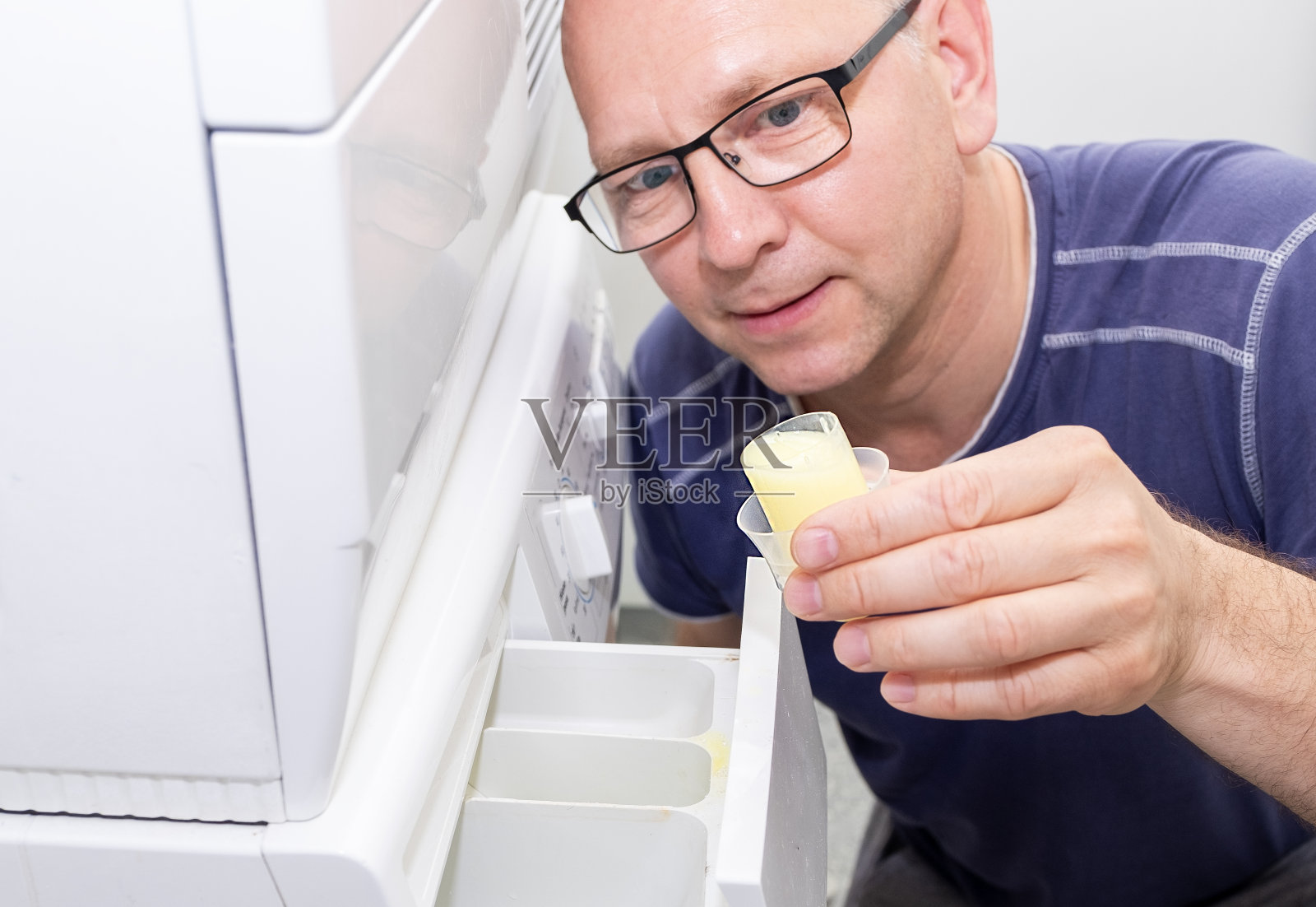 白人男子在洗衣机里使用衣物柔顺剂的特写。照片摄影图片