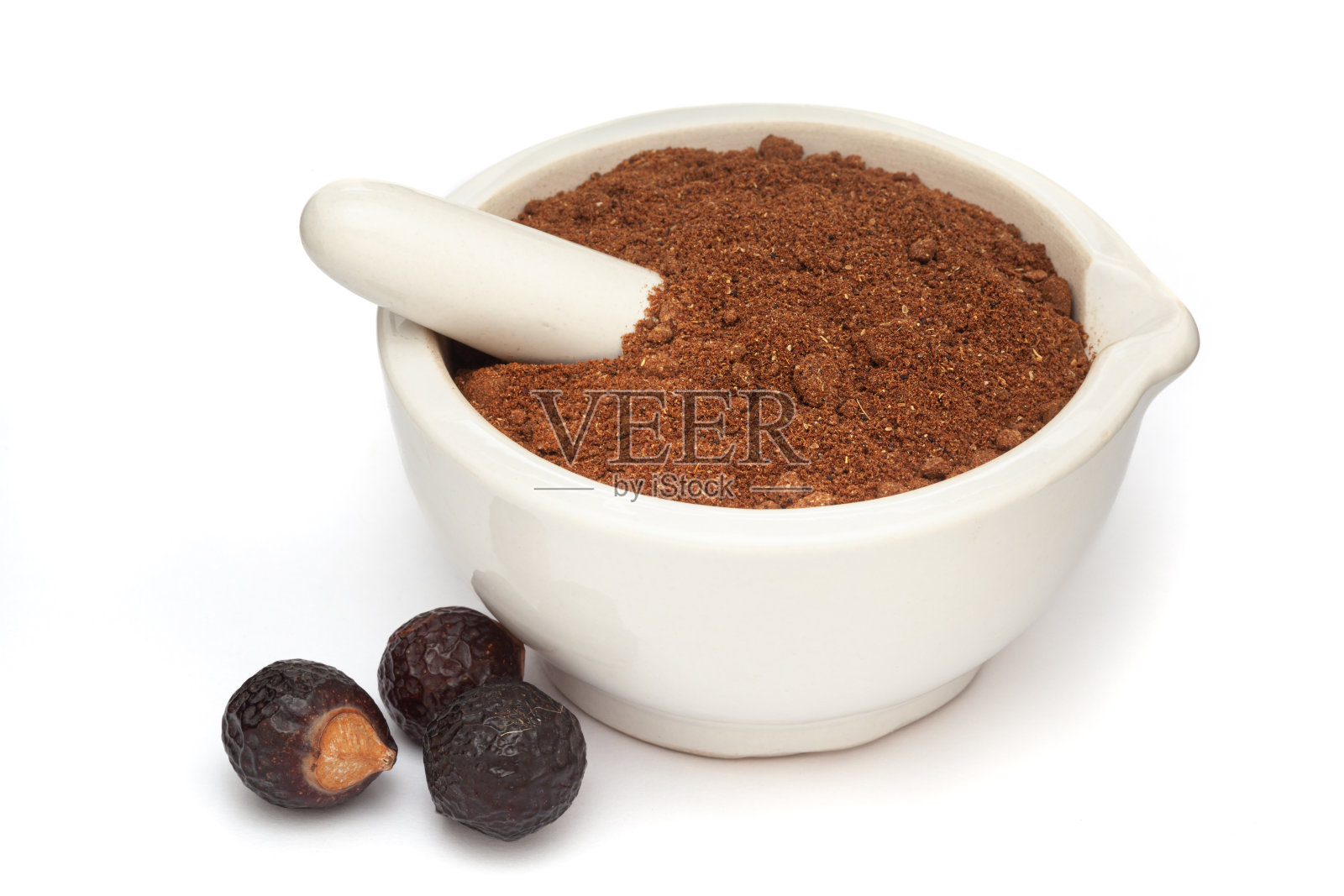 有机皂子(Sapindus mukorossi)粉末及其果实的特写，在白色的陶瓷砂浆和杵中，分离在白色的背景上。照片摄影图片