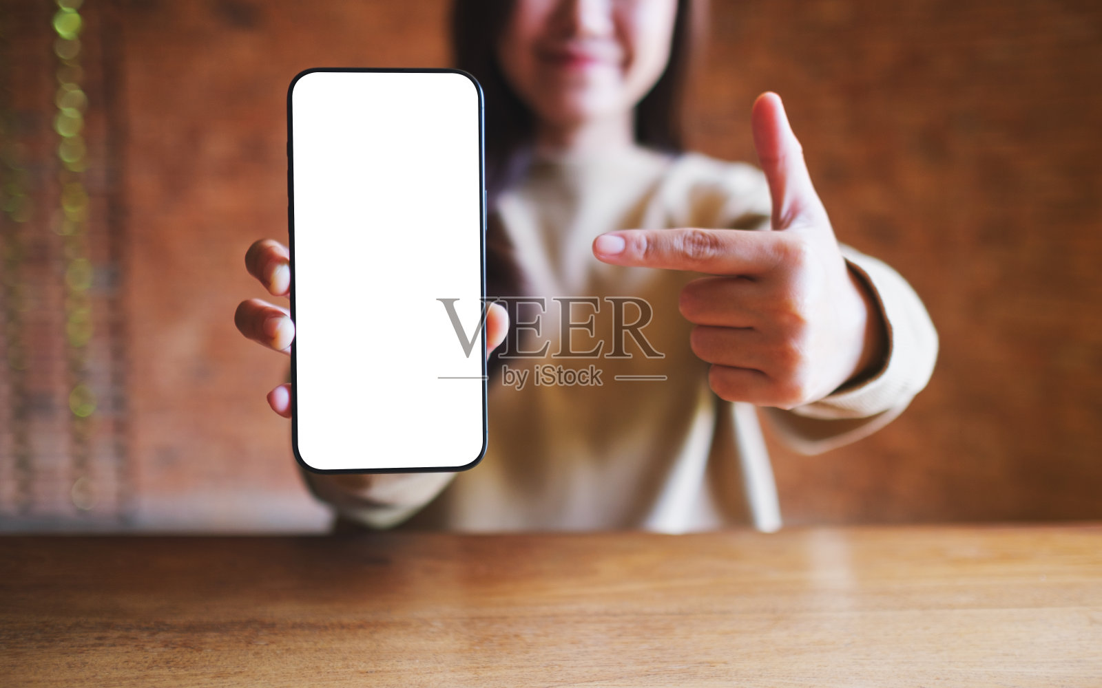 一名年轻女子拿着手机，用手指指着屏幕空白的手机照片摄影图片