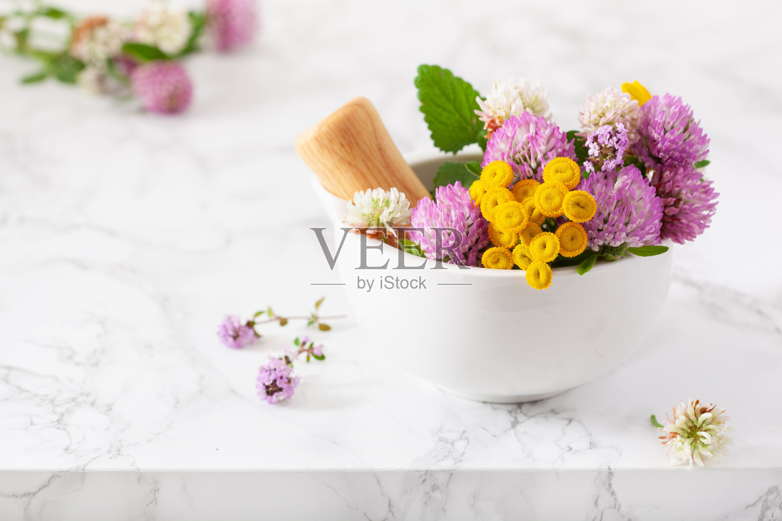 药用花在臼中草药，替代医学。三叶草，三色堇，玫瑰月桂照片摄影图片