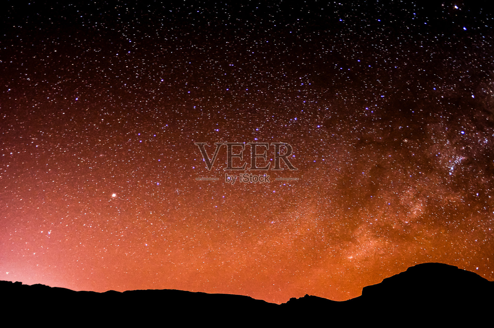 黑暗的天空点缀着几颗星星，背景是一座小山照片摄影图片