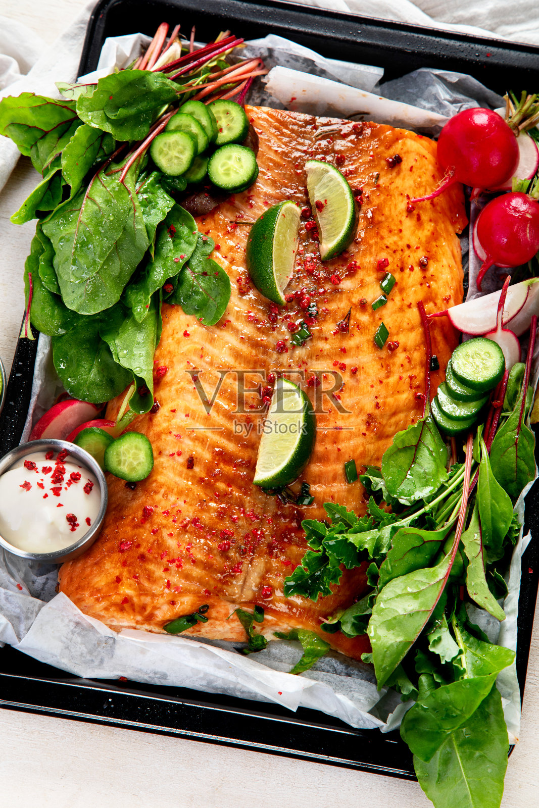 用新鲜蔬菜和酸橙煮鲑鱼。烤红鱼轻木制背景照片摄影图片