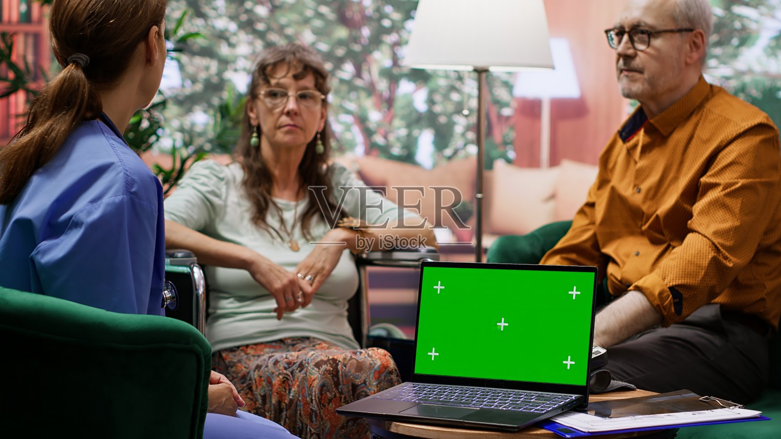 护工在绿幕旁边的轮椅上咨询老妇人照片摄影图片