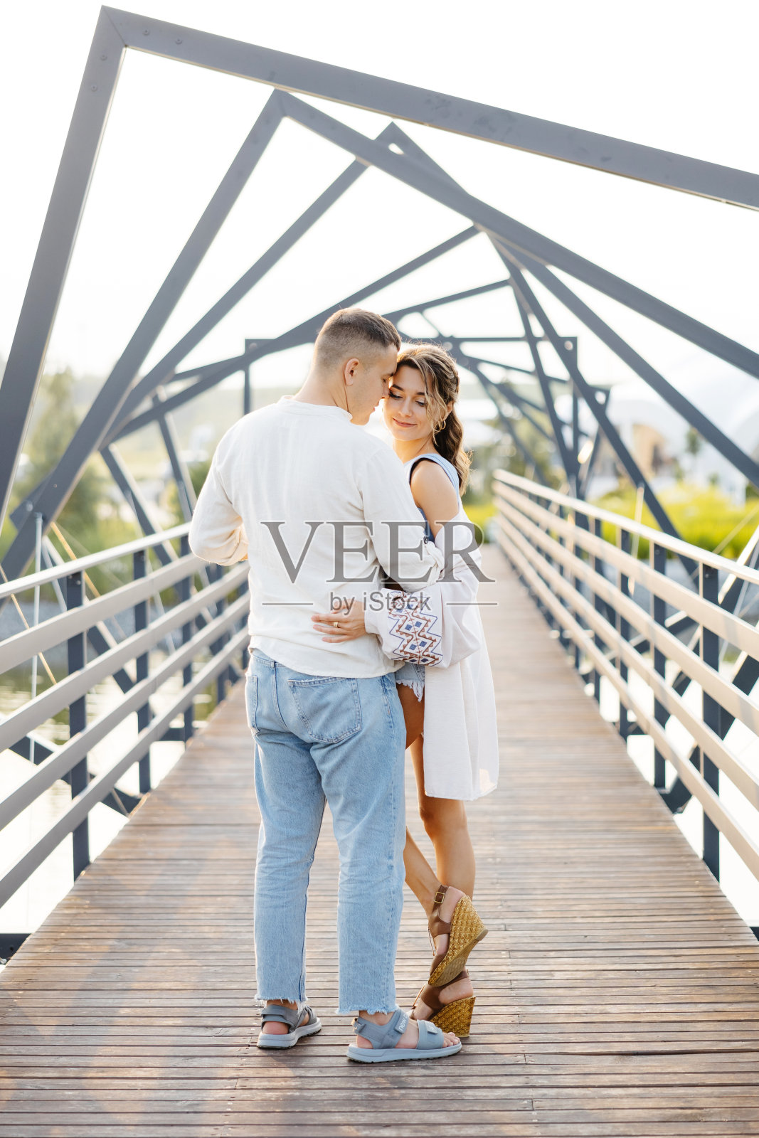 一对恩爱的夫妇在光滑的现代桥上温柔地拥抱着对方，象征着他们深厚的联系和感情照片摄影图片