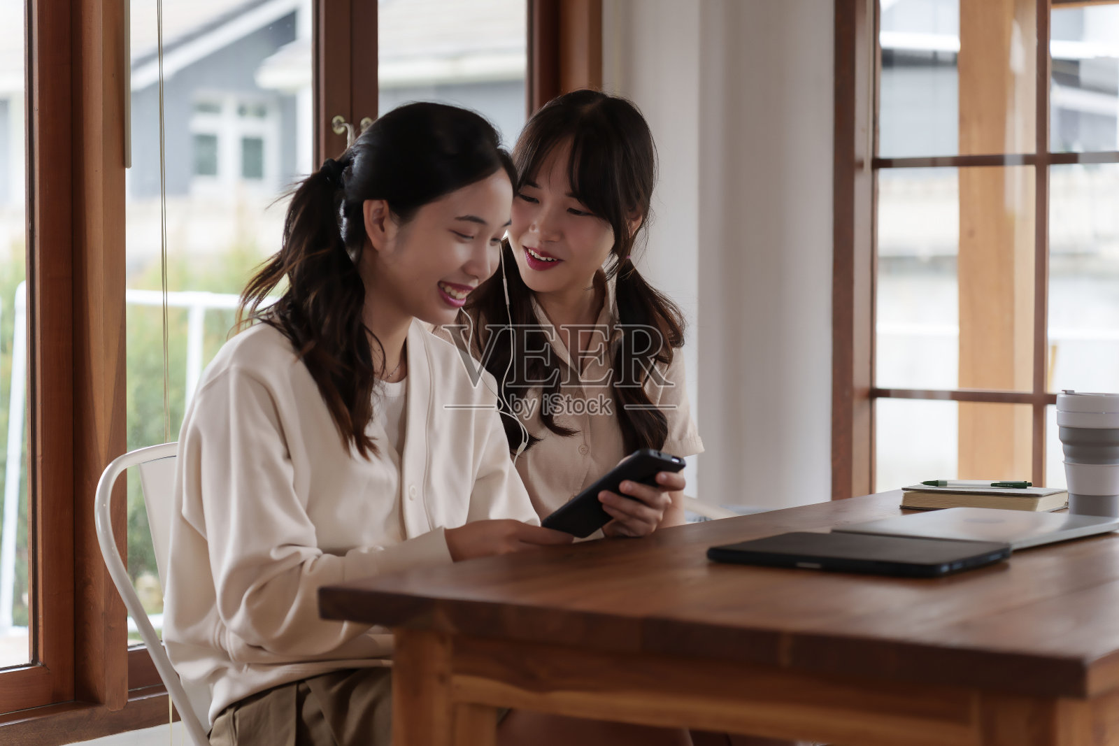 两个大学同学坐在一张木桌旁，一起学习照片摄影图片