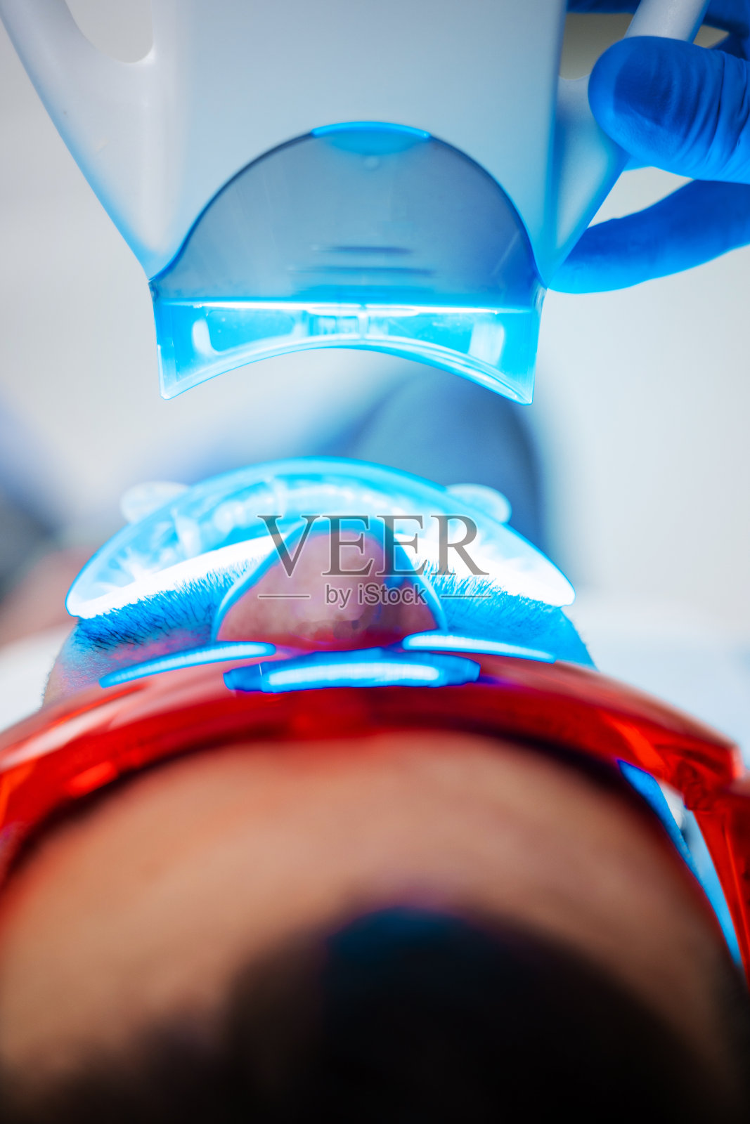 牙医正在用紫外线口腔器械给病人美白牙齿。牙齿紫外线美白过程。照片摄影图片