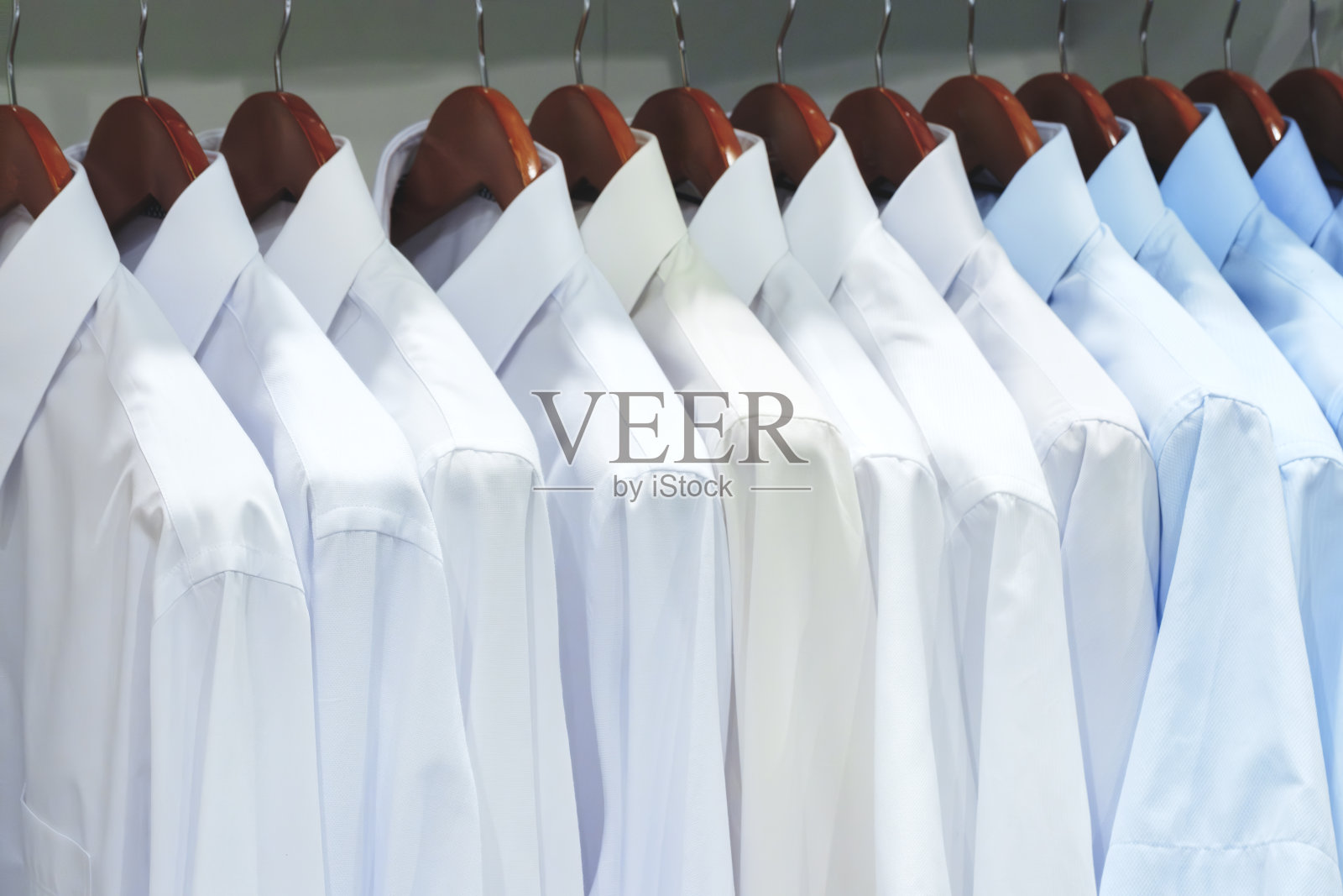 男士衬衫悬挂的特写照片。衣服挂在架子上。衣架与衬衫。男士职业装照片摄影图片