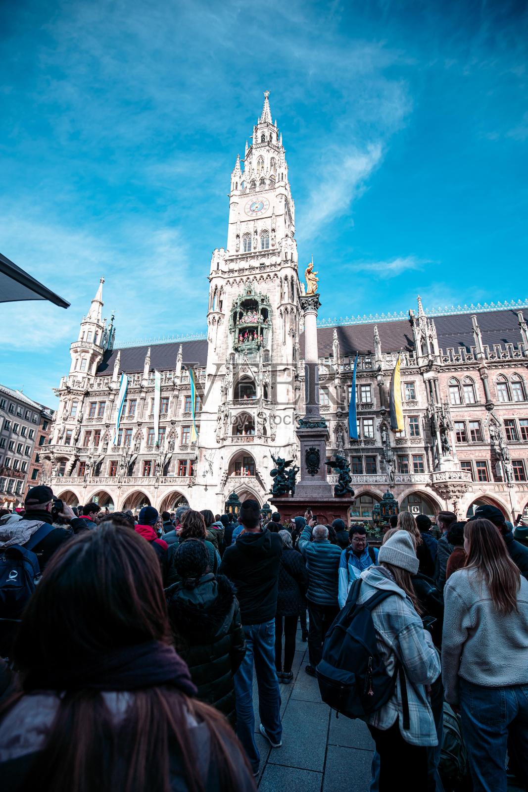 在德国慕尼黑，一群人聚集在一起观看钟楼复杂的表演。照片摄影图片