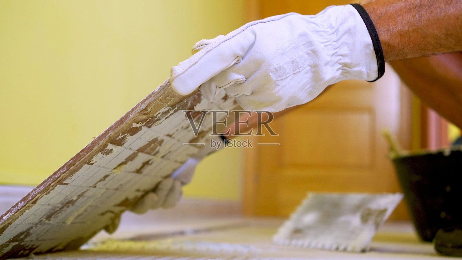 建筑工人的手在地板上用水泥铺瓷砖的特写照片摄影图片