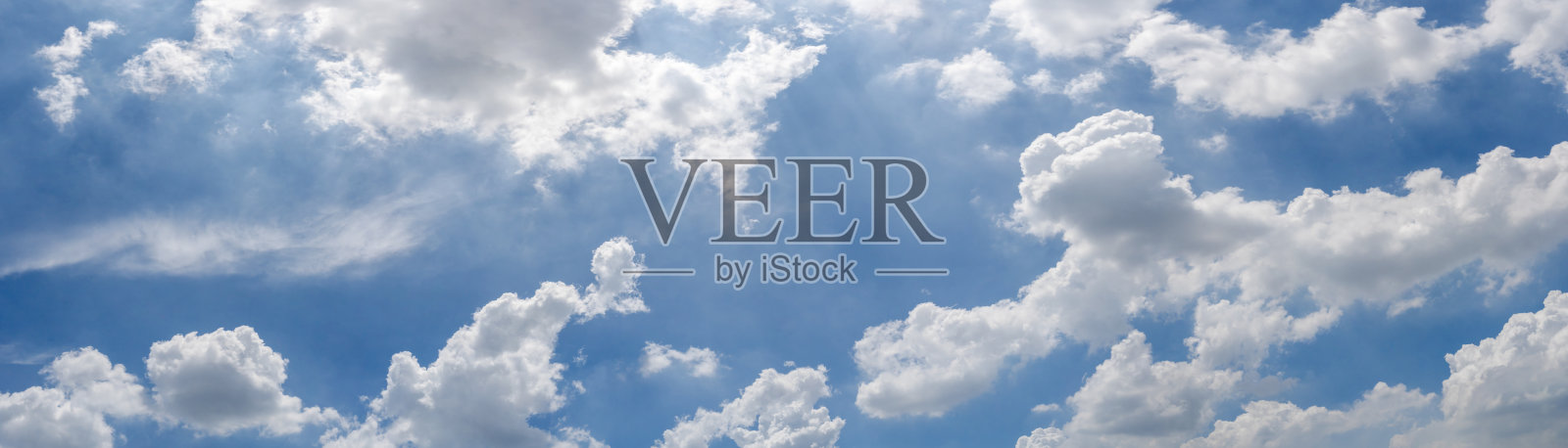 天空是蓝色的，零星地飘着几朵云。云是白色的，蓬松的。照片摄影图片