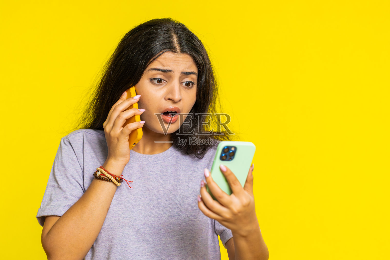 心烦意乱的女商人一边讲着两部手机，一边发生谈话冲突争吵照片摄影图片