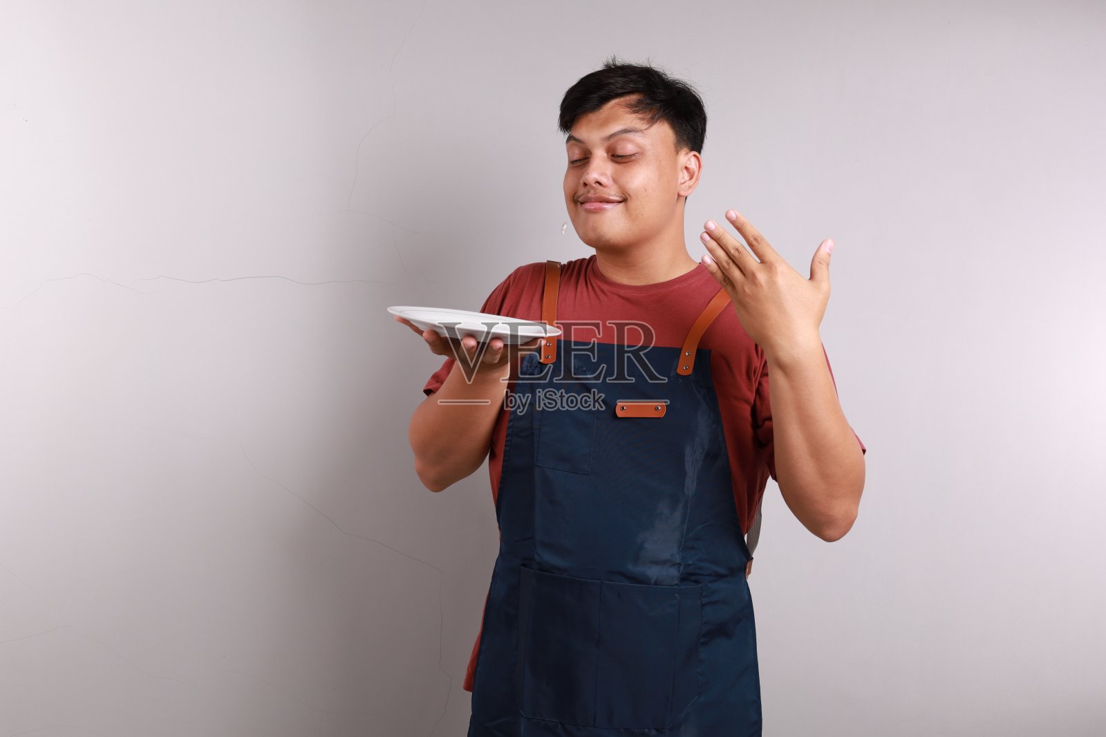 近距离的亚洲男子在围裙上呈现的东西在她的空白色盘子，复制空间餐菜单的概念。照片摄影图片