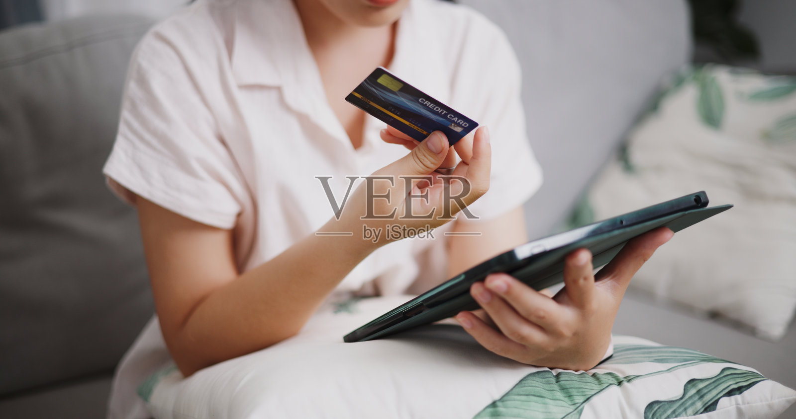 年轻女子在家用信用卡和平板电脑在线支付。照片摄影图片