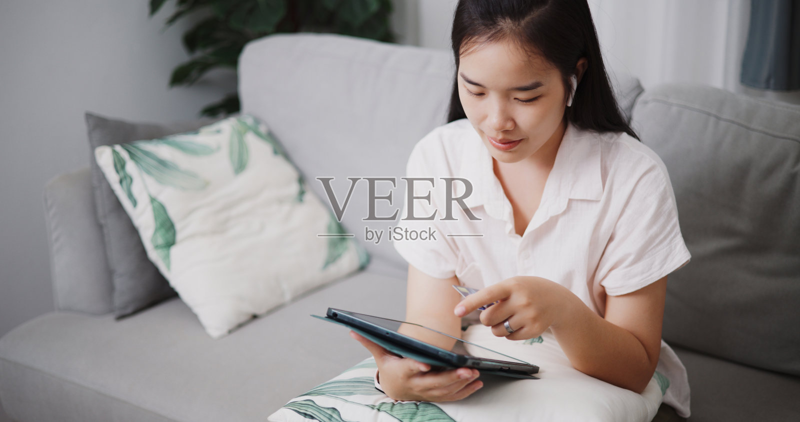 年轻女子在家用信用卡和平板电脑在线支付。照片摄影图片