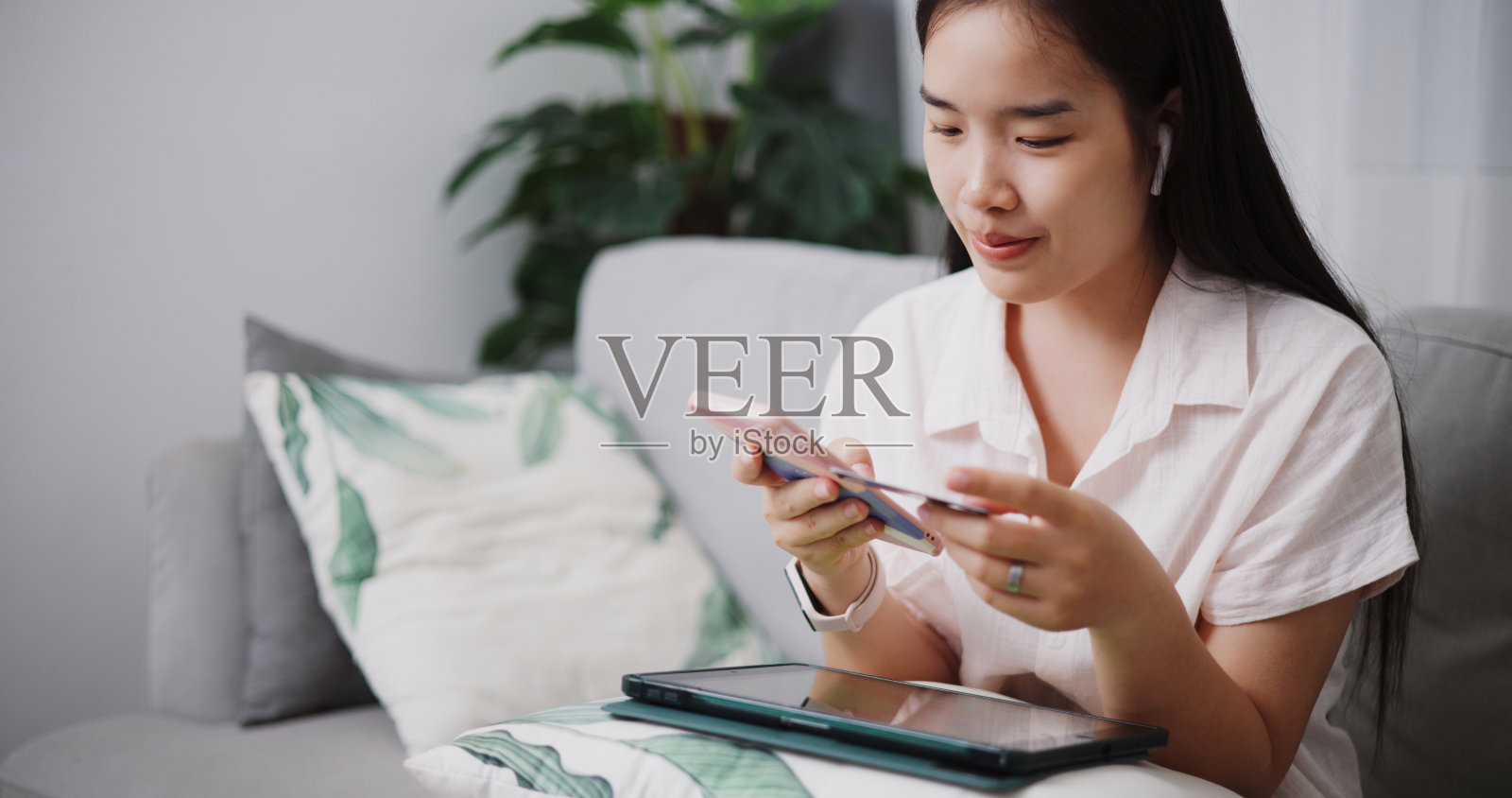 年轻女子用信用卡和手机在家网上购物。照片摄影图片