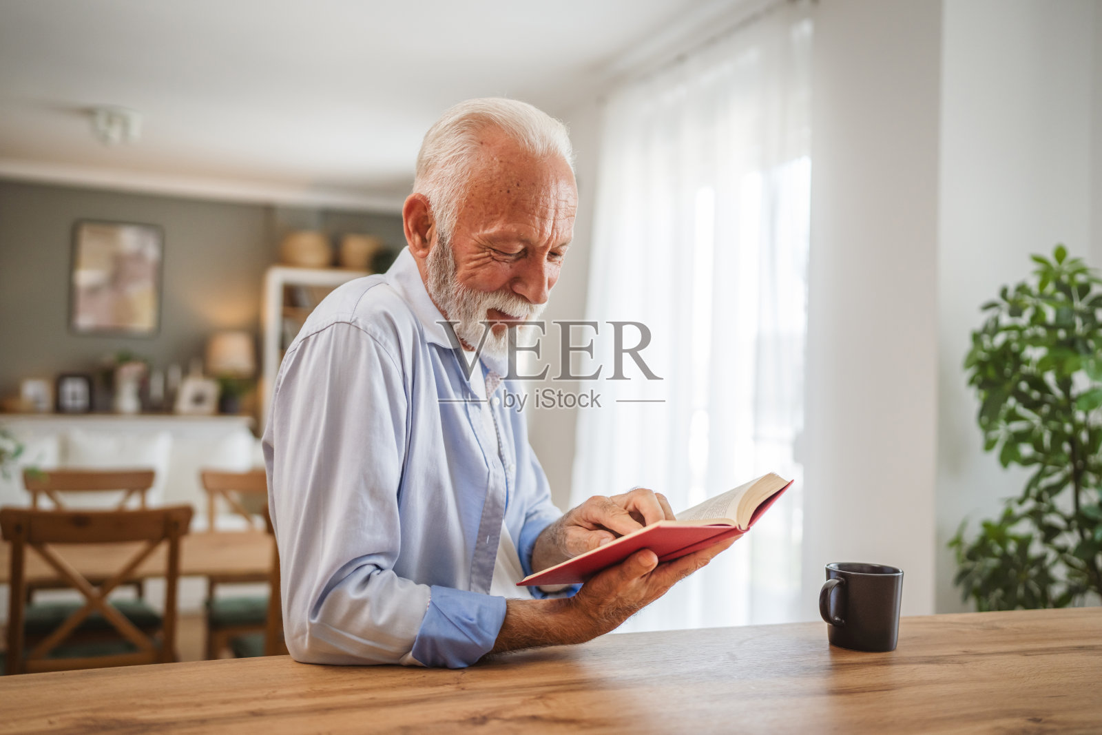 年长的白种人在家里看书，喝杯咖啡照片摄影图片