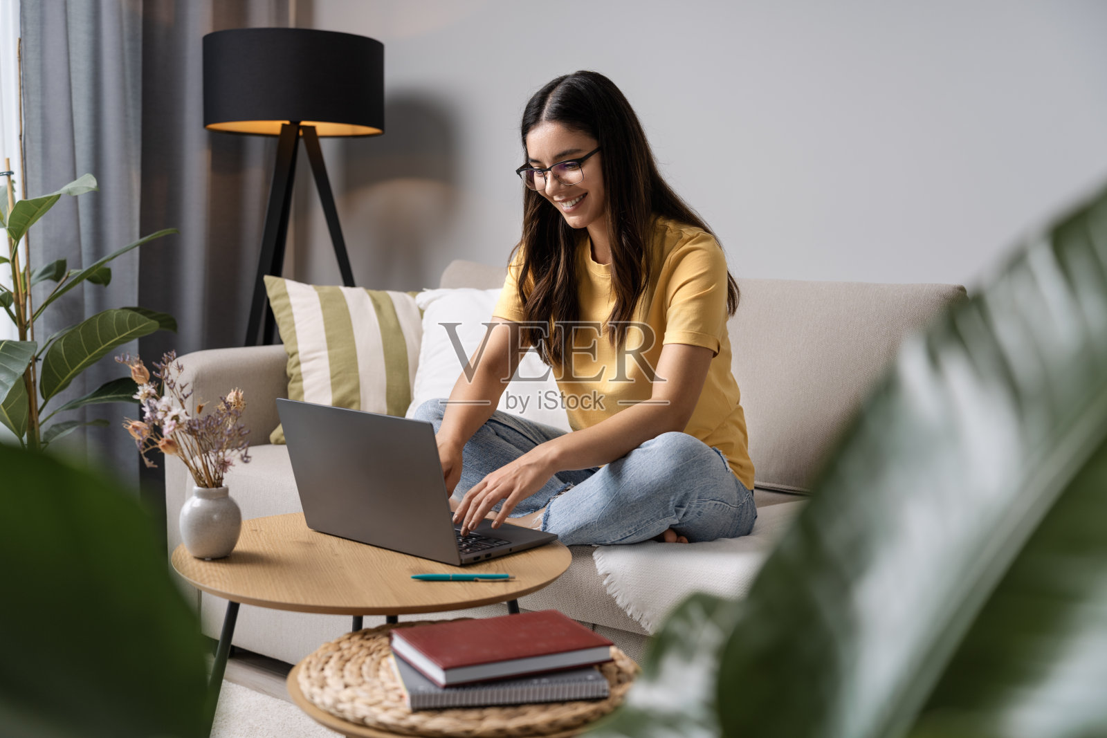 研究别致。这个女孩坐在舒适的沙发上做作业，满脸笑容照片摄影图片