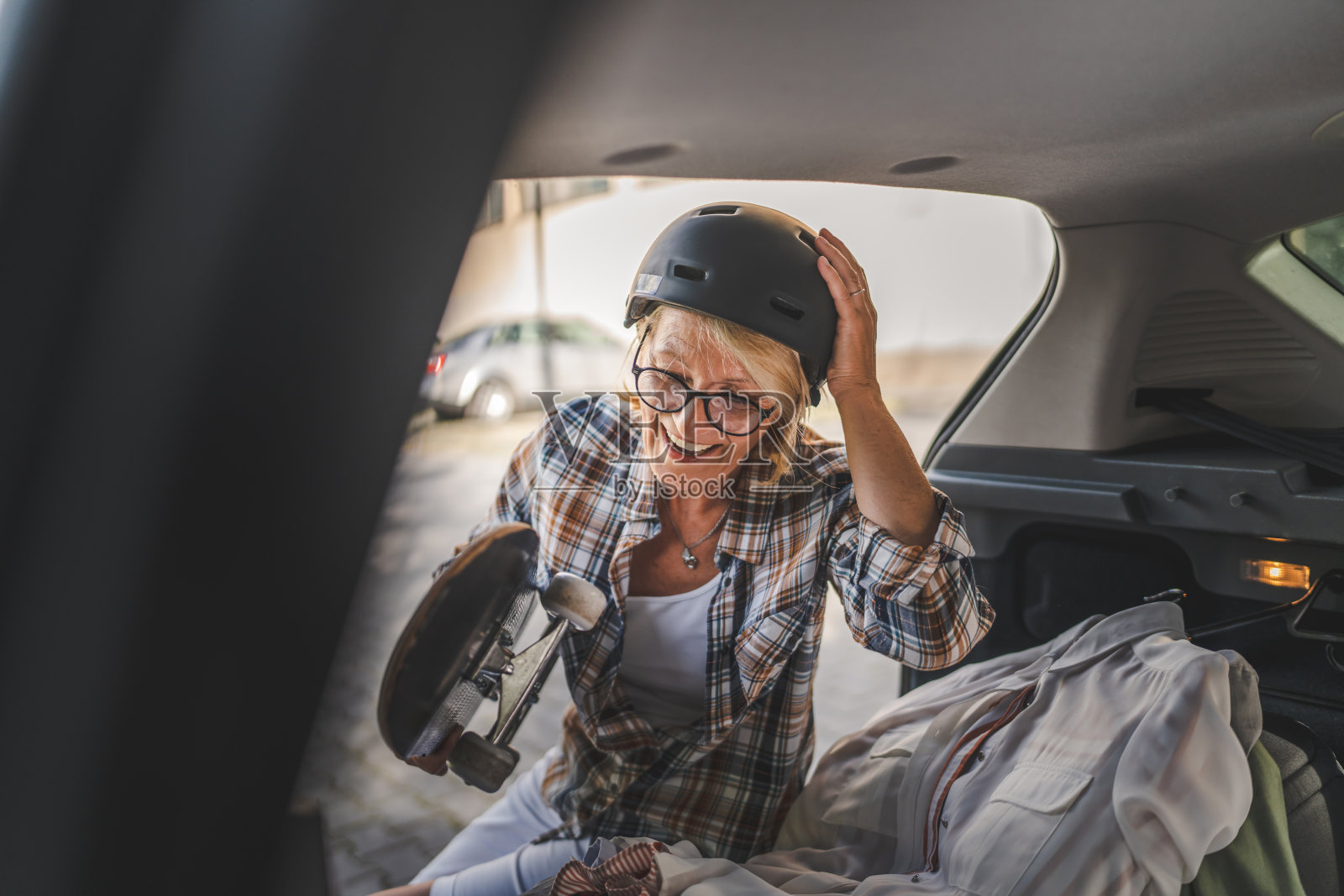 成熟的金发女子旅行时从汽车后座拿东西照片摄影图片