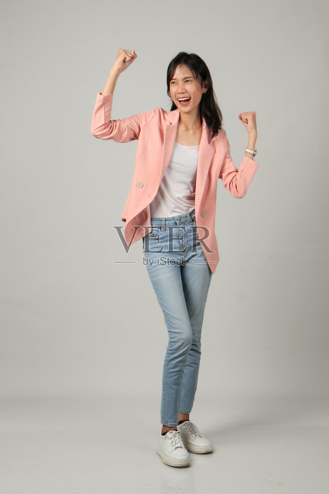 全镜头拍摄快乐的亚洲妇女举起她的拳头。在孤立的背景下穿着正式的休闲装照片摄影图片