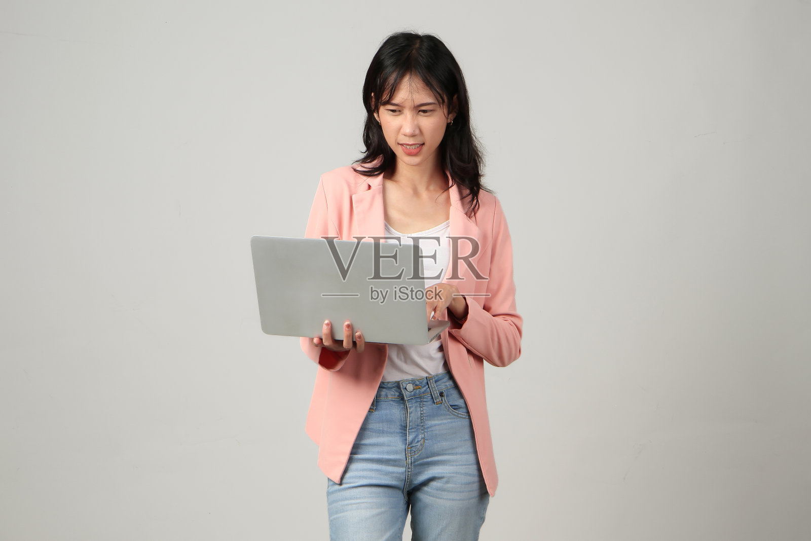 沉思的亚洲女人拿着笔记本电脑，在孤立的背景下做着思考的手势照片摄影图片