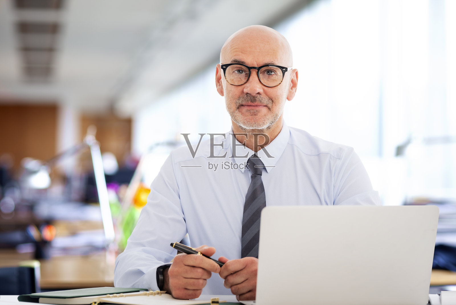 一个中年商人坐在办公桌前，用笔记本电脑工作的肖像照片摄影图片