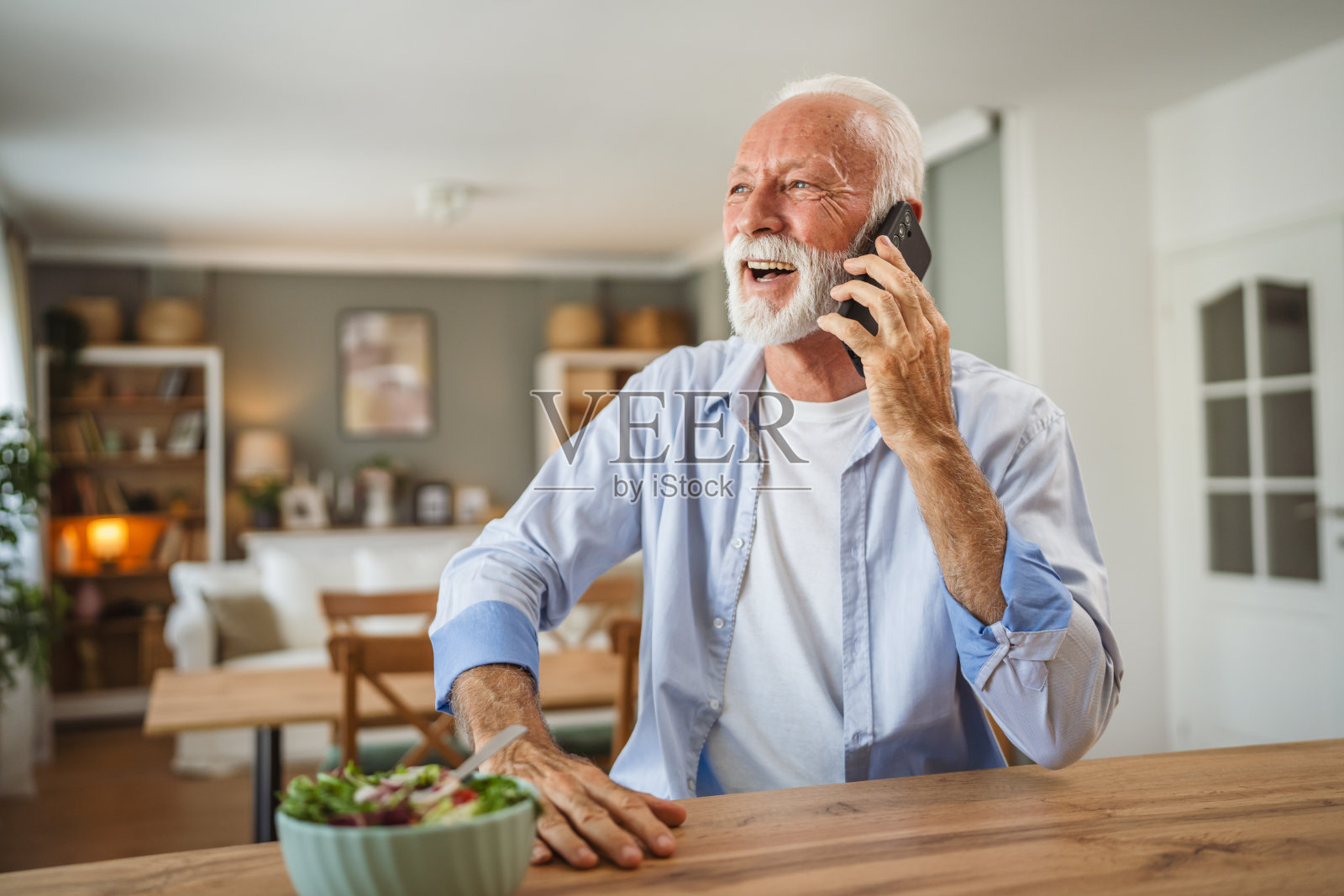 老人一边在家吃沙拉一边打电话照片摄影图片
