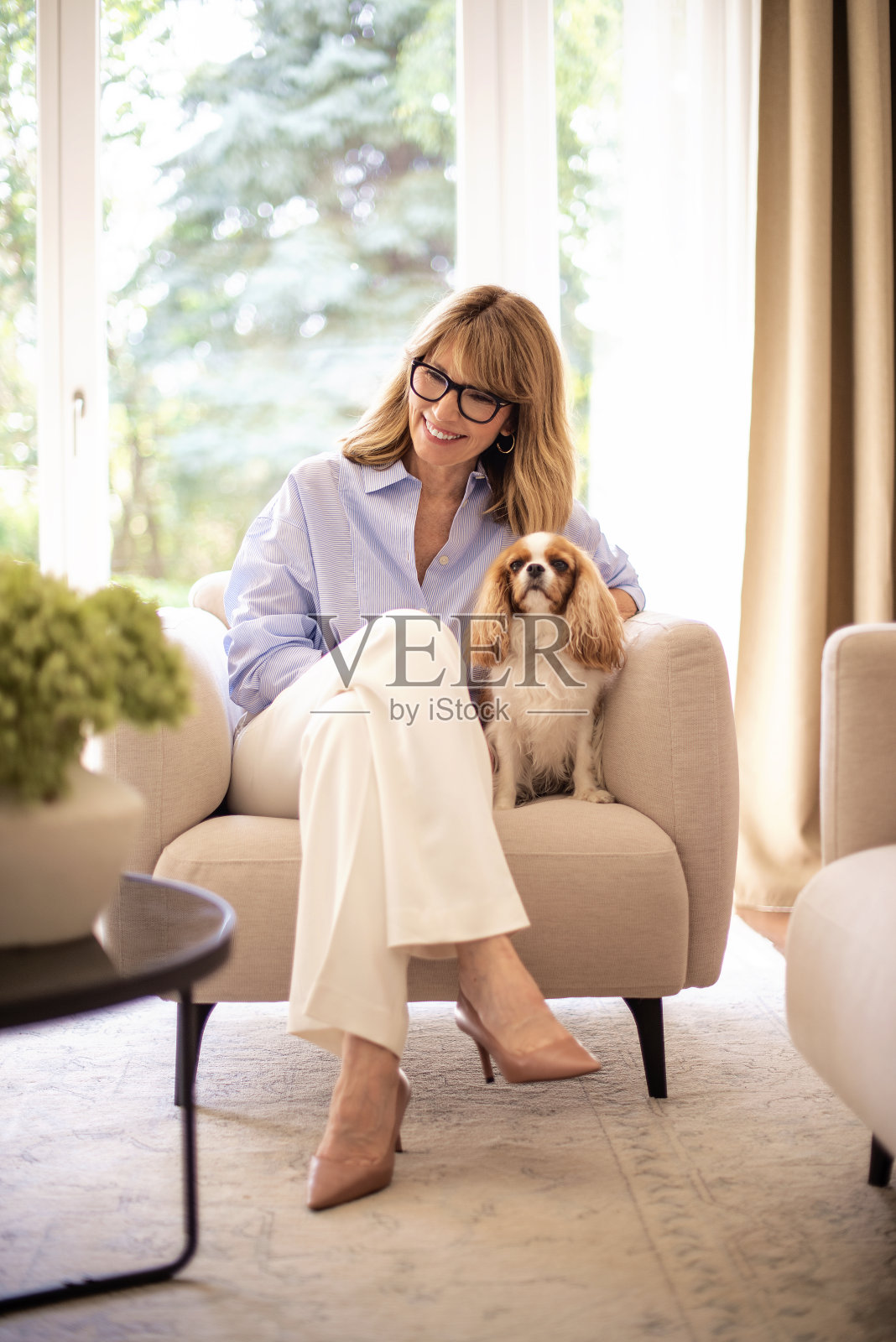 金发中年妇女和她可爱的小狗在家里放松照片摄影图片