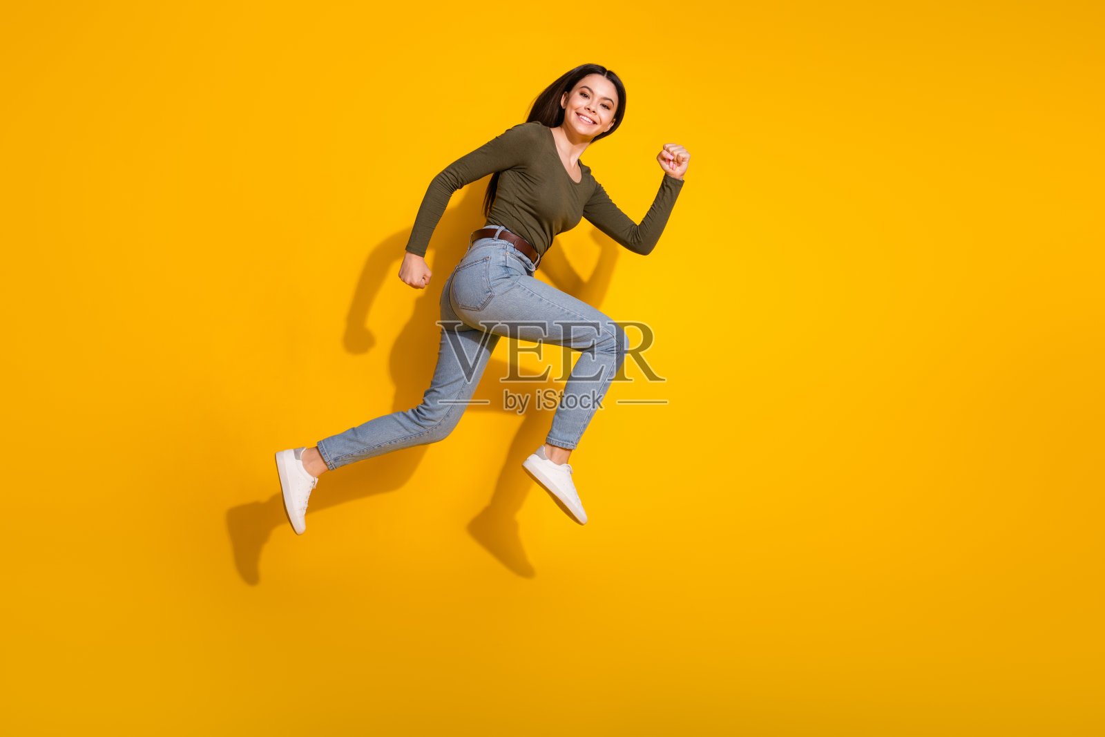 照片中，漂亮的少女露出v字舌头，穿着黄色背景的时髦卡其布服装照片摄影图片