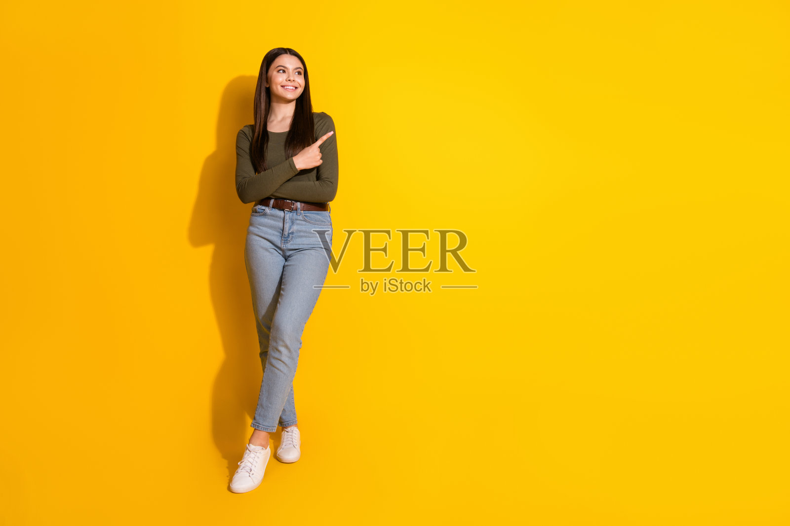 漂亮的十几岁的女孩的全尺寸照片点空看穿时髦的卡其装孤立在黄色的背景照片摄影图片