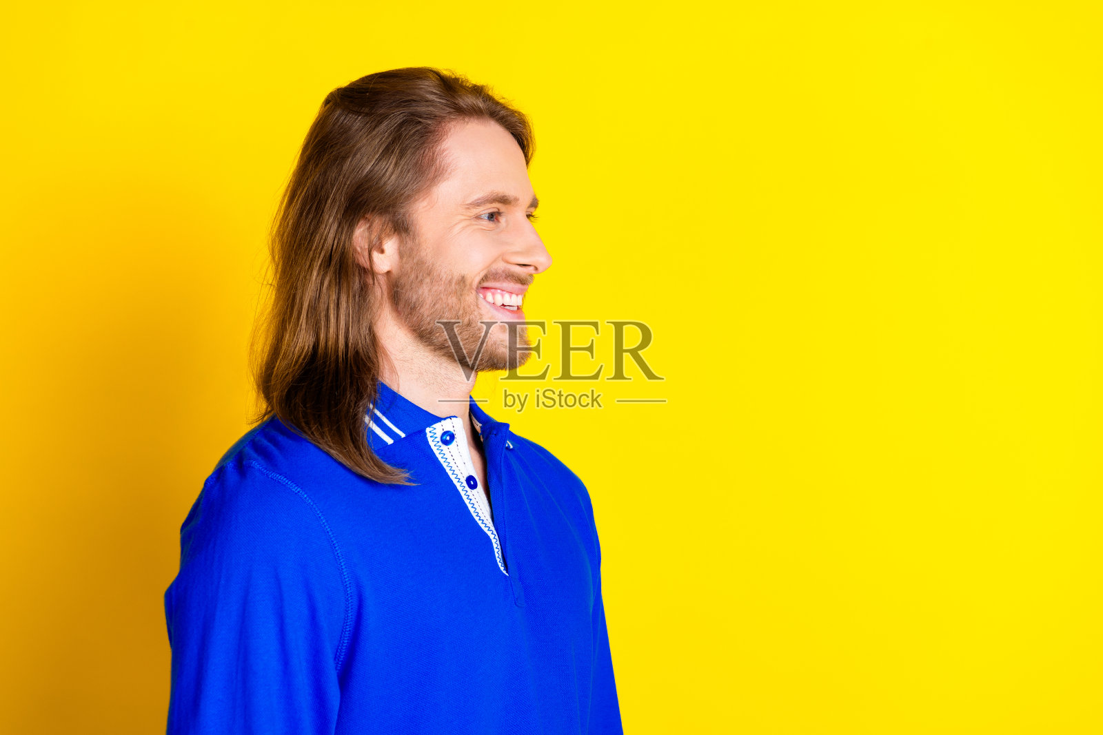 照片中帅气帅气的男子穿着蓝色时髦的衣服套头衫，在黄色的背景上显得空旷孤立照片摄影图片