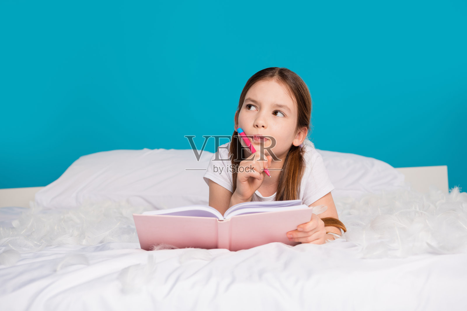 梦幻的漂亮可爱的女孩躺在舒适的床想象的空白空间孤立的蓝色背景的照片照片摄影图片