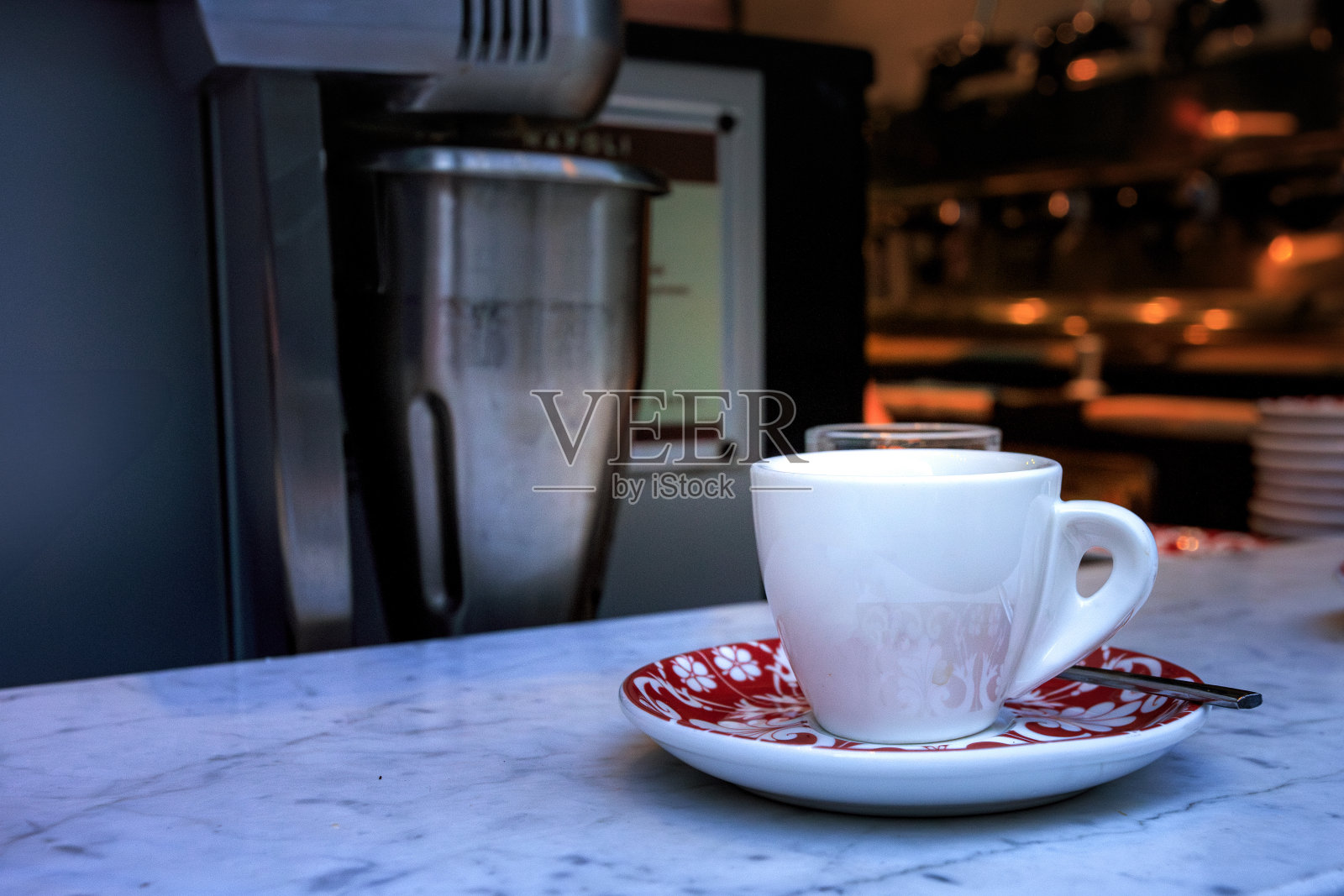 白色的咖啡杯放在大理石柜台上的红白相间的盘子上照片摄影图片