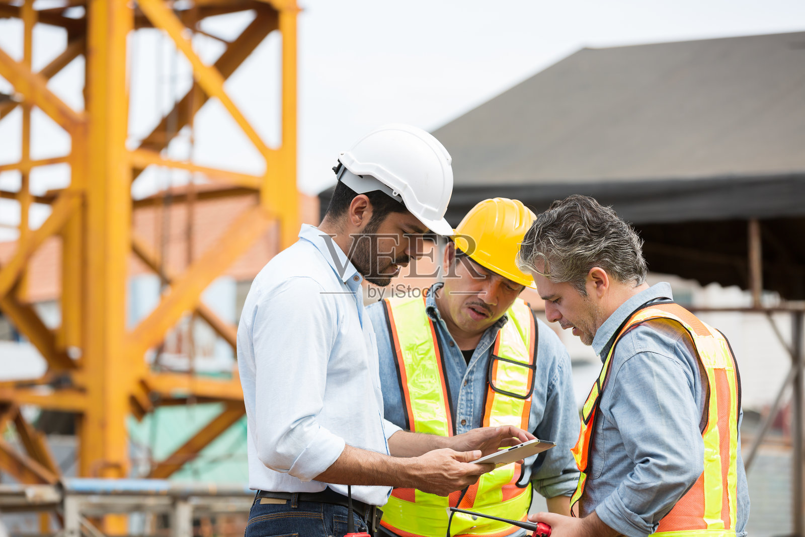 男工程师队伍在施工现场进行建筑结构施工和讨论。一群在建筑工地工作的男性建筑工人照片摄影图片