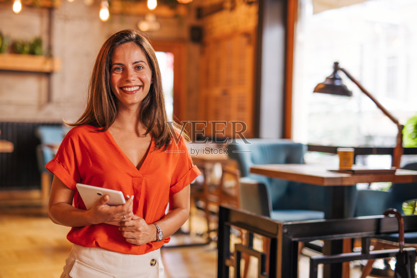 一个年轻女子站在自助餐厅的肖像，她是老板。一个成功的小企业主。她拿着一块写字板照片摄影图片