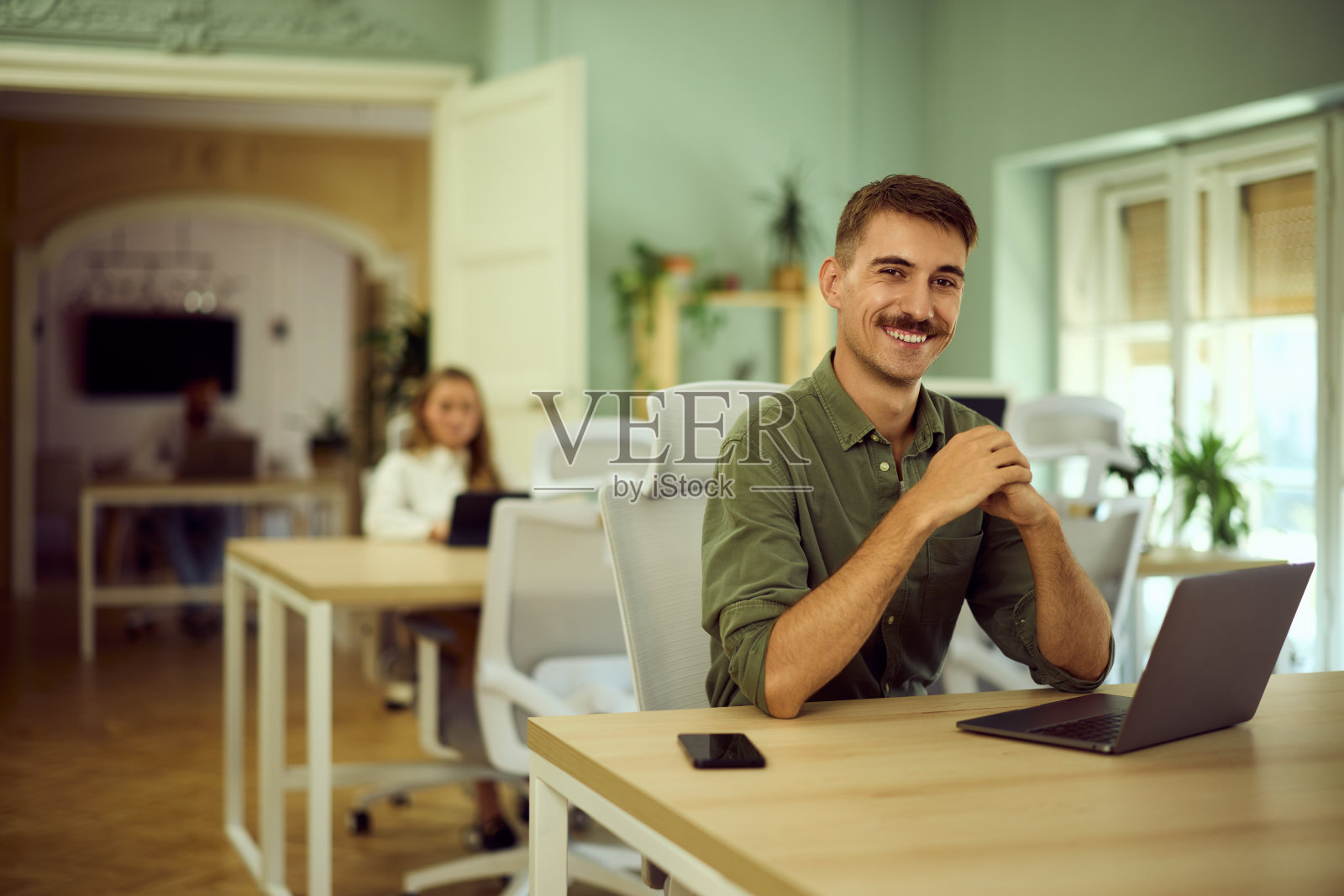 在联合办公空间工作的自由职业者在镜头前摆姿势。照片摄影图片