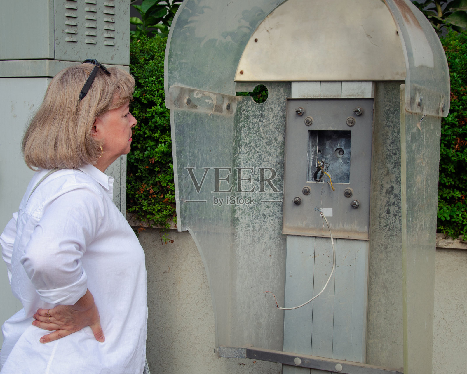 昔日的回响：妇女观看被拆除的公用电话亭，回忆时光飞逝照片摄影图片