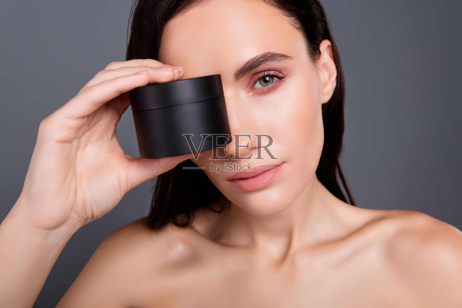 近距离照片的黑发女子覆盖眼睛与奶油罐孤立的灰色背景照片摄影图片