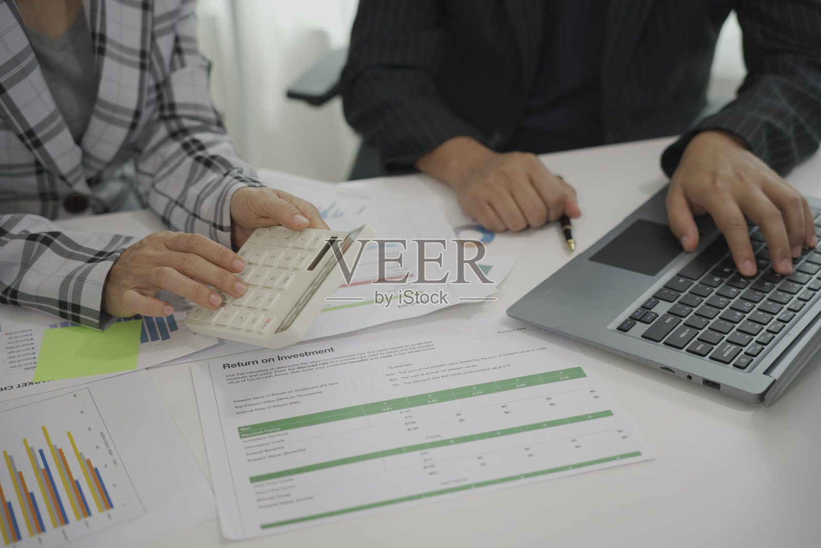 两个商人开会，用平板电脑在桌子上的纸上分析财务报告，并分析电力仪表盘显示。在你的平板电脑屏幕上的商业见解照片摄影图片