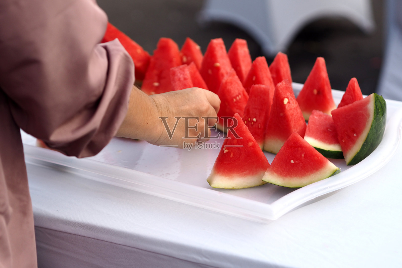 一个人的手在桌子上捡西瓜的特写，很适合写文章照片摄影图片