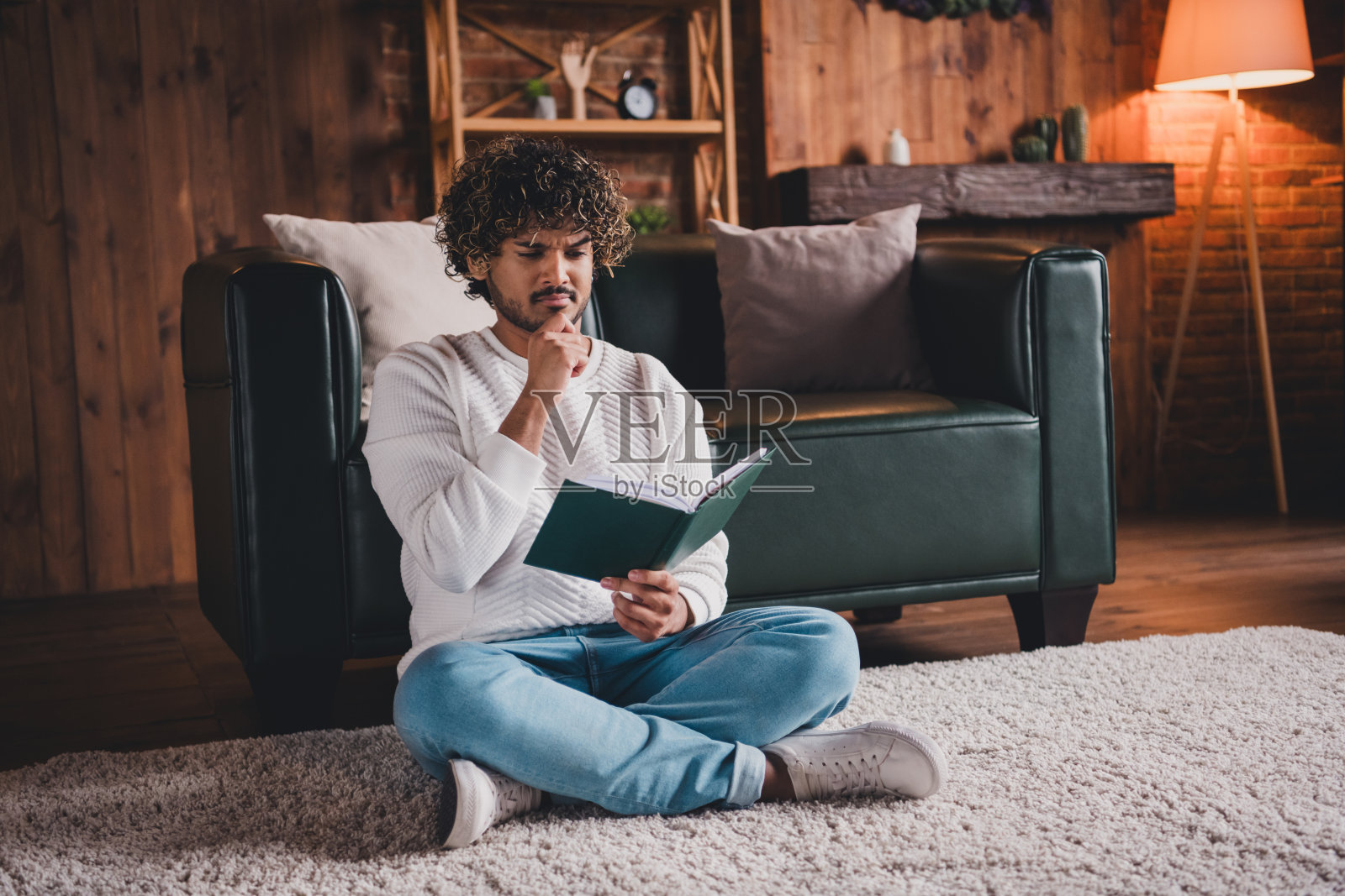 有魅力的可疑男子穿着白色运动衫在房间里看书的照片照片摄影图片