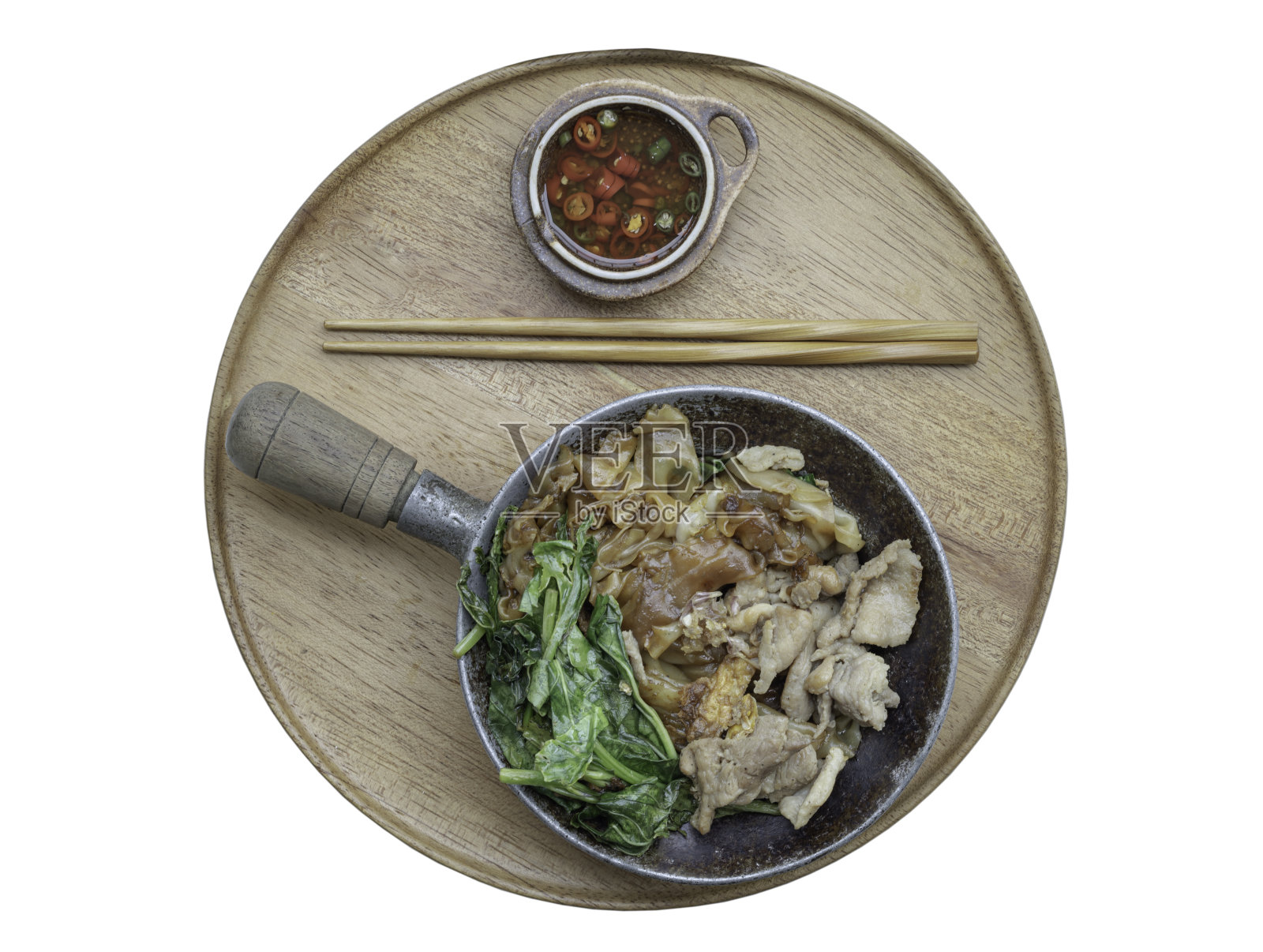 甜酱油炒米粉(Pad See-Ew)，用筷子和泰国辣椒鱼露盛在圆形木制托盘上，白色背景上有夹道。照片摄影图片