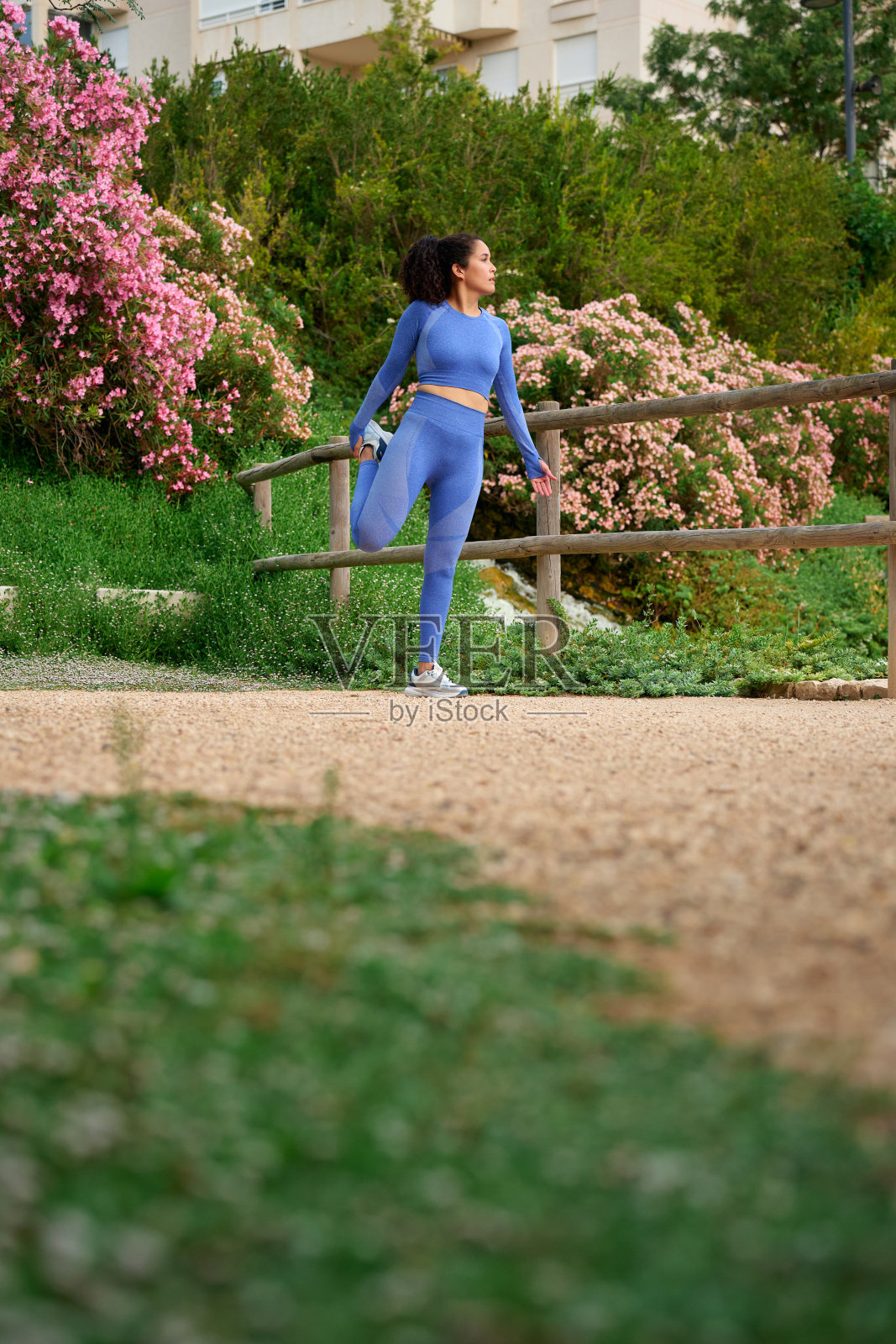 穿着蓝色运动服的女人在瀑布边伸展身体照片摄影图片